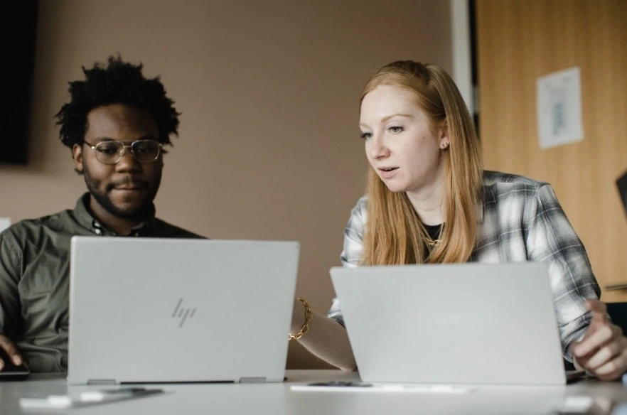 Photograph of co-workers looking at laptops in Media Tradecraft's office.